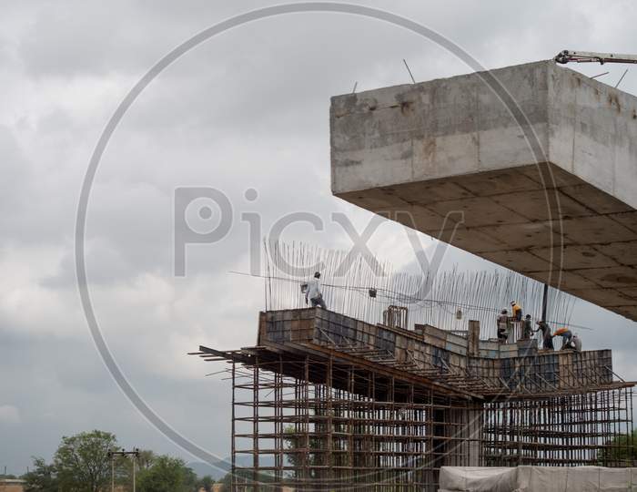 Labor And Workers Standing On A Support For A Bridge Under Construction With Rebar Support Frame Visible