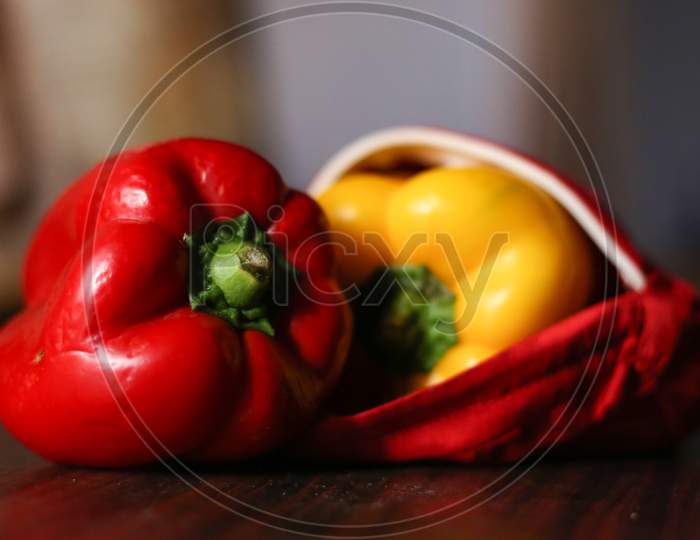 Closeup View Of Red And Yellow Color Bell Peppers In An Red Color Cloth With Wooden Background
