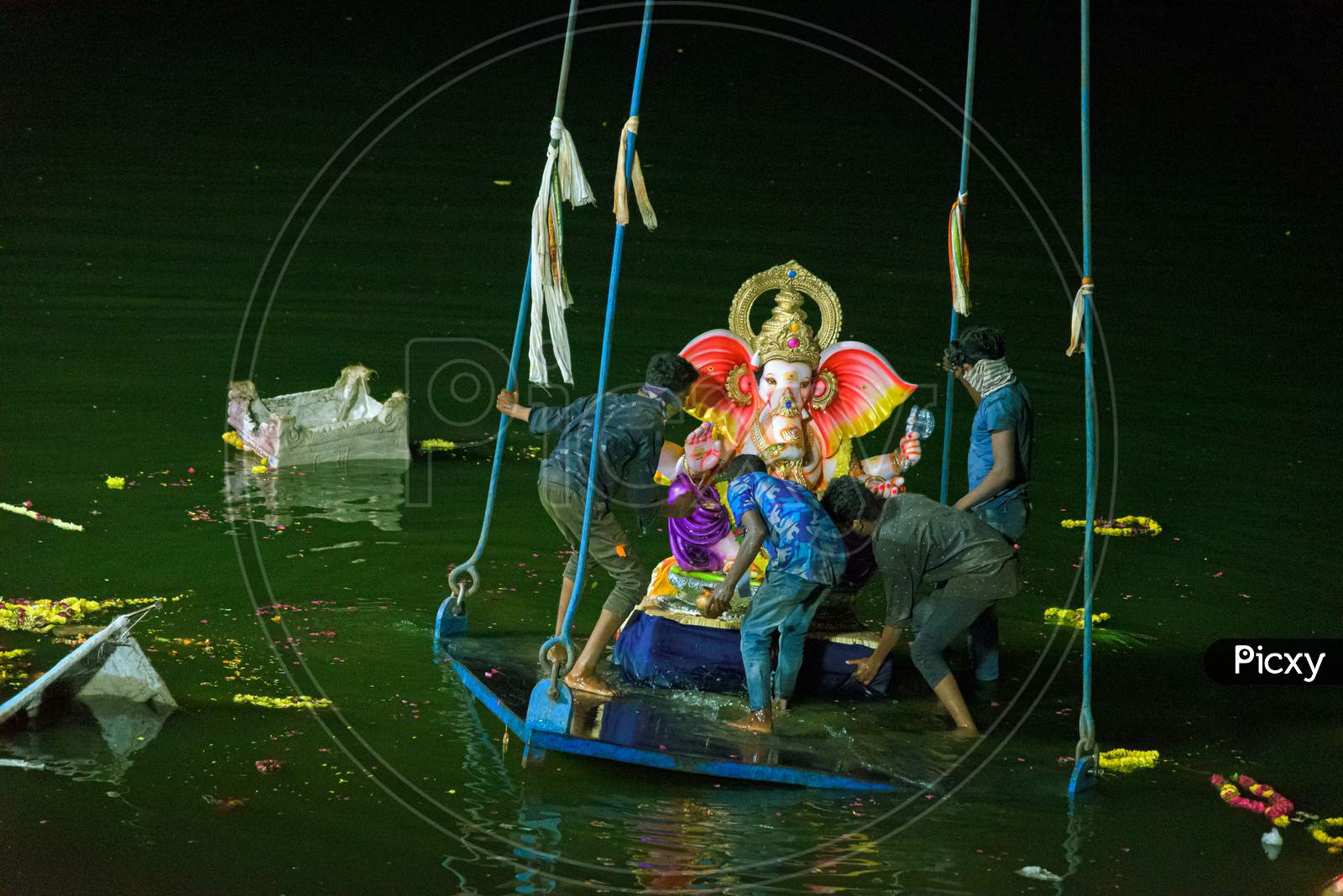 Group of people pushing the ganesh idol into the hussaina sagar to immerse ,hyderabad 2020