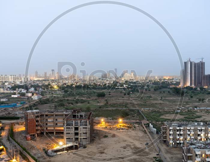 Aerial Dusk Shot Of Buuldings With Warm Orange Lights Shining Out Of The Newly Constructed Homes Offices And Residences
