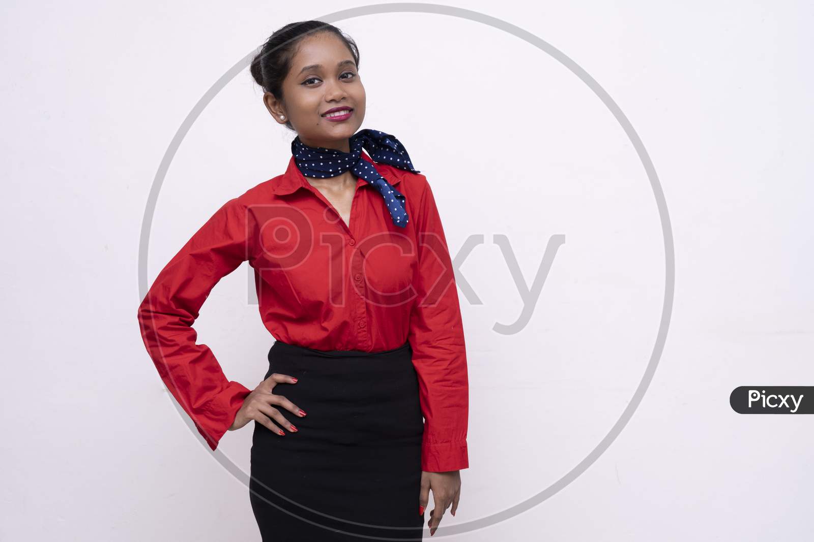 Young Charming Air Hostess In Red Dress With Blue Collar Posing In Front Of The Camera With White Background And Copy Space.