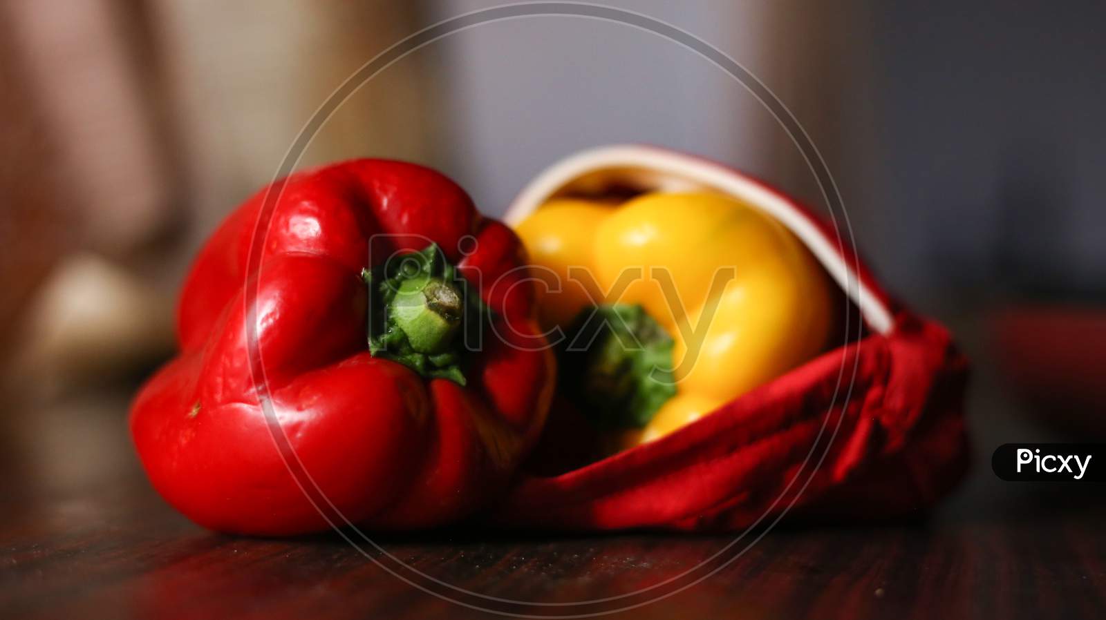 Closeup View Of Red And Yellow Color Bell Peppers In An Red Color Cloth With Wooden Background