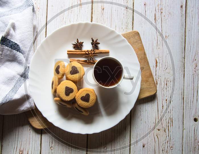 View from top of  pile of cookies along with a cup of coffee in a white plate