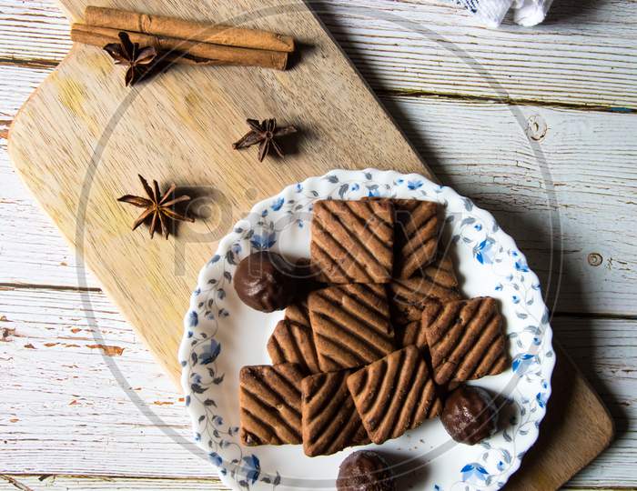 Tasty chocolate cookies and chocolates on a wooden platter