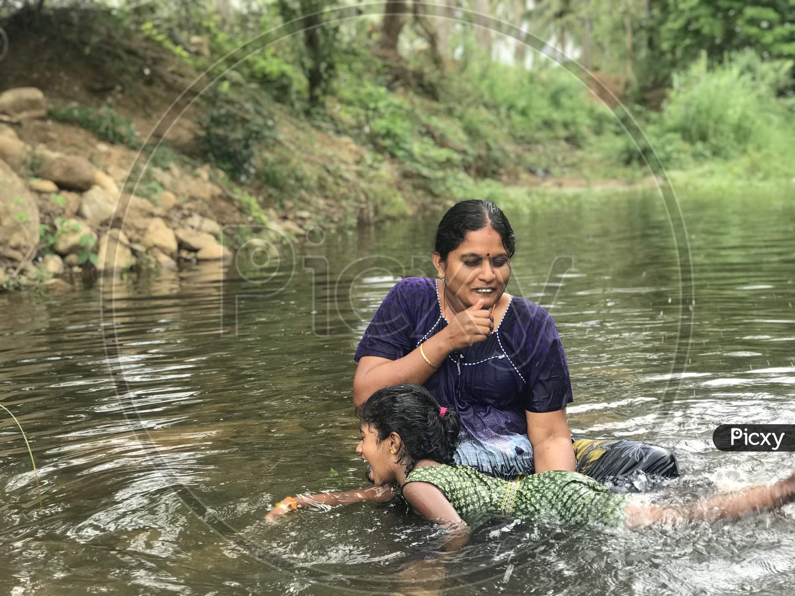 Mother Teaching Swimming To Her Daughter In An Natural River