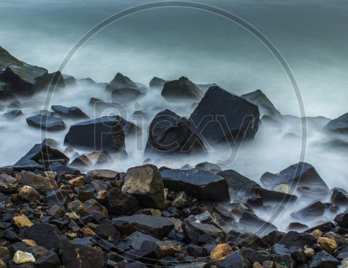 Long Exposure Of Mist Around Rock On The Seaside In The Morning