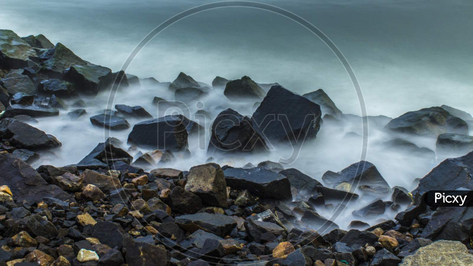 Long Exposure Of Mist Around Rock On The Seaside In The Morning