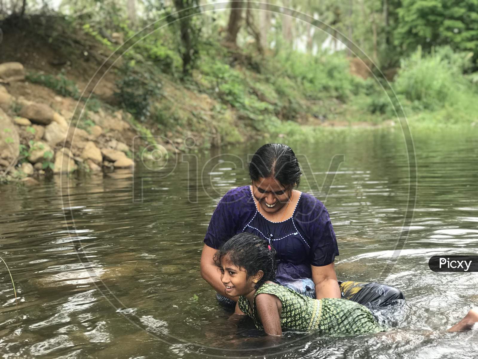 Mother Teaching Swimming To Her Daughter In An Natural River