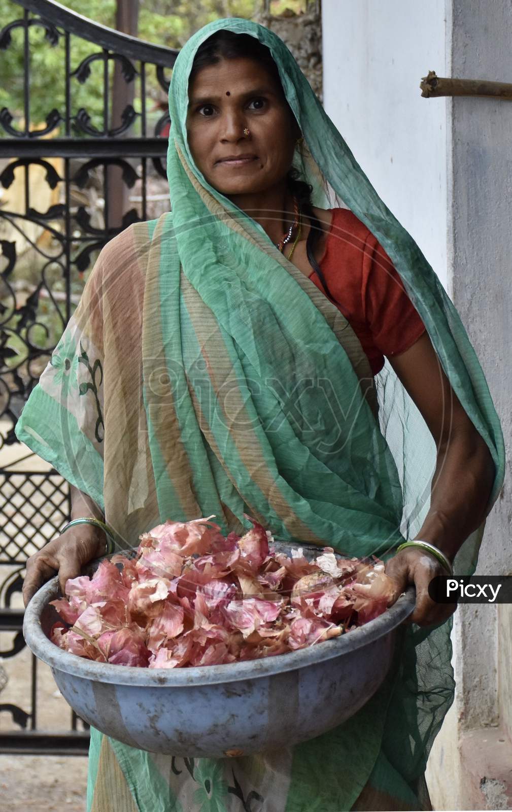 Indian Woman Holding A Tub Of Onion Peels