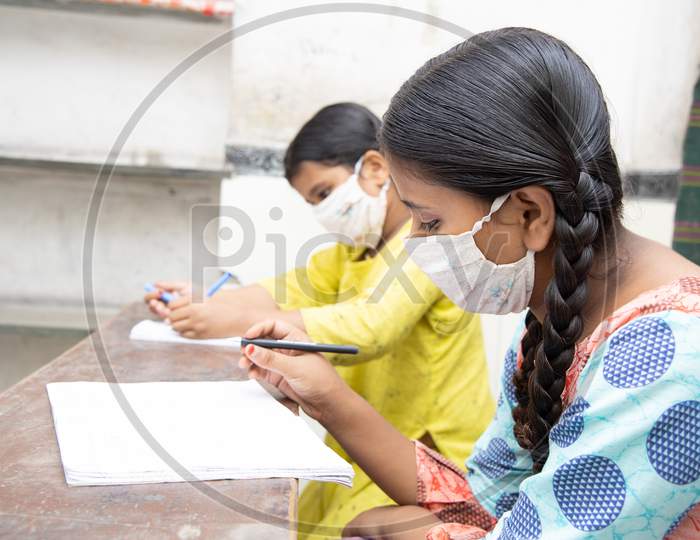 Indian female Studying In Classroom Wearing Mask And Social Distancing, school reopen during covid19 pandemic