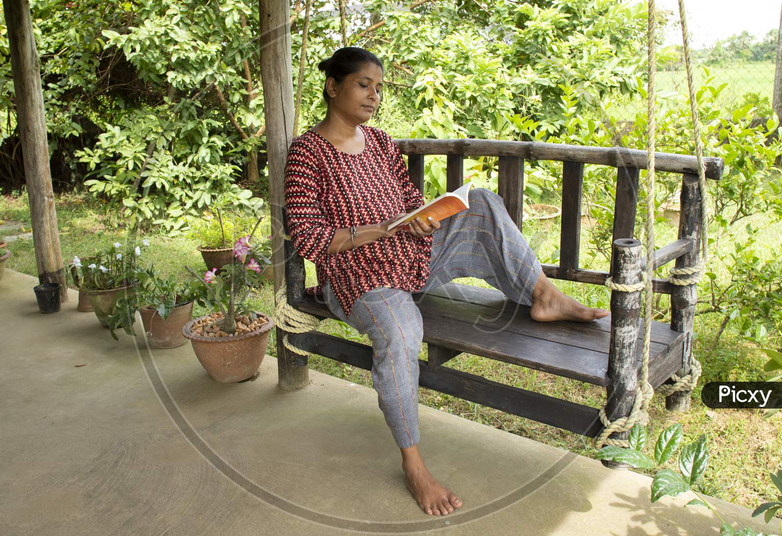 Image of Woman on swing reading a book-QY774115-Picxy