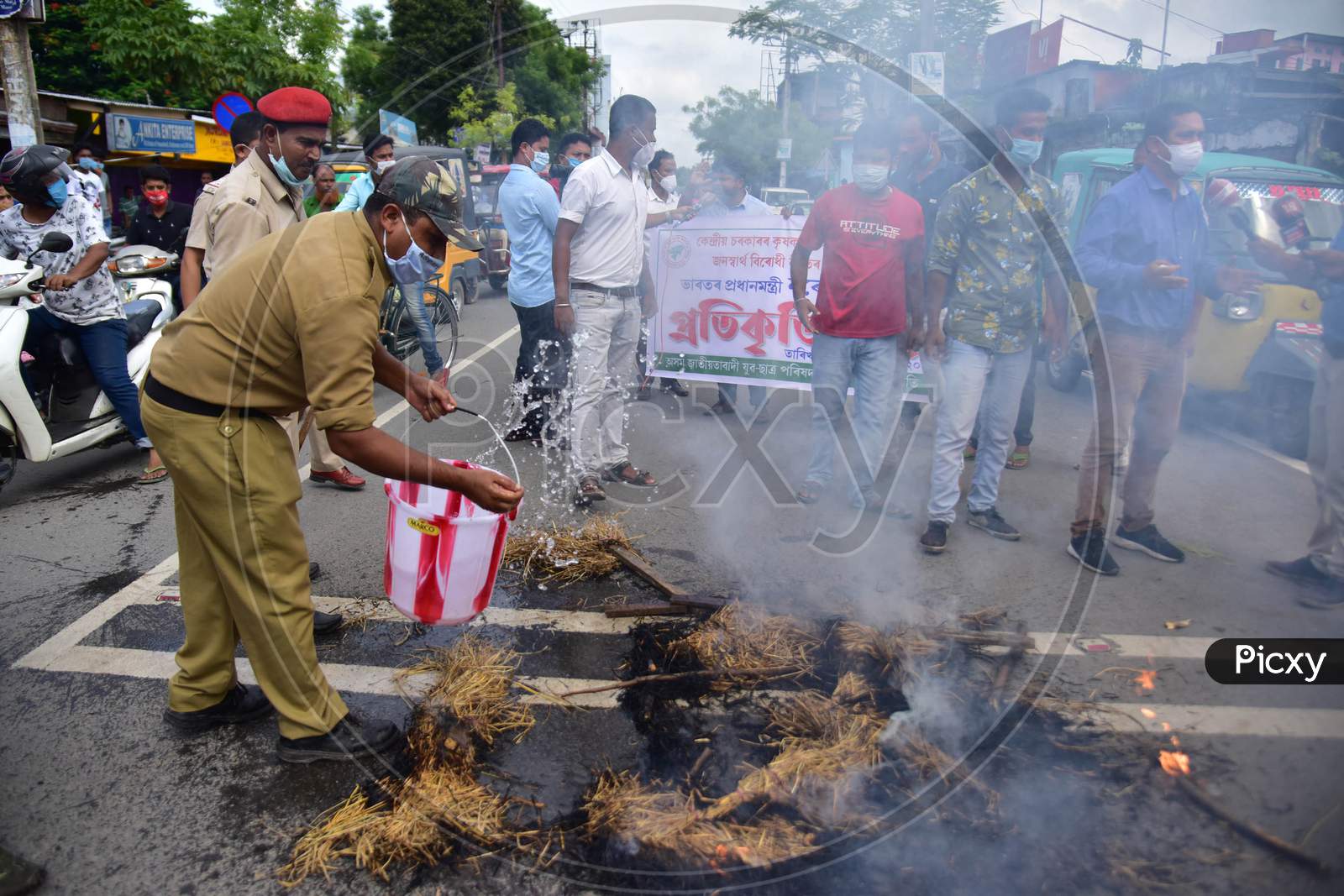 A police personnel douses an effigy set ablaze by the Asom Jatiyatabadi Yuba Chatra Parishad (AJYCP) activists during a protest against recent farm bills in Nagaon District of Assam on Sep 23,2020.