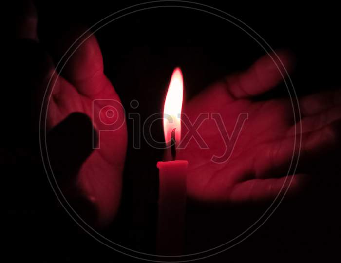 Hands Supporting Flame Of Candle At Night