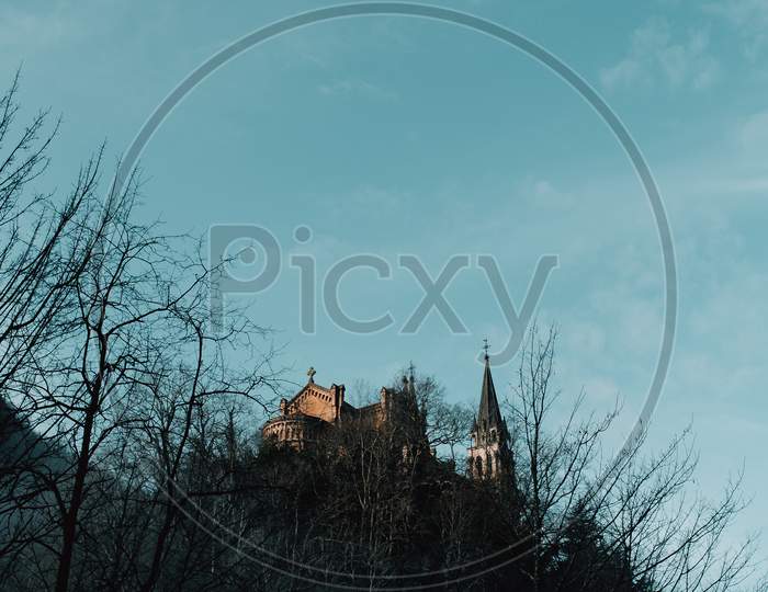 Medieval Castle On The Top Of A Hill With Tree Silhouettes And A Clear Sky With Copy Space Covadonga