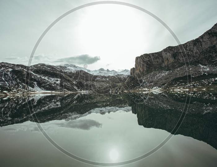 Mountain Range Reflecting In A Frozen Lake During The Winter With Copy Space In The North Of Spain