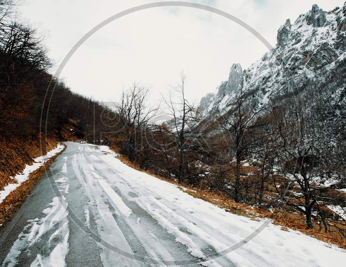 Road On The Mountains Covered With Snow And A Mountain Range As The Background