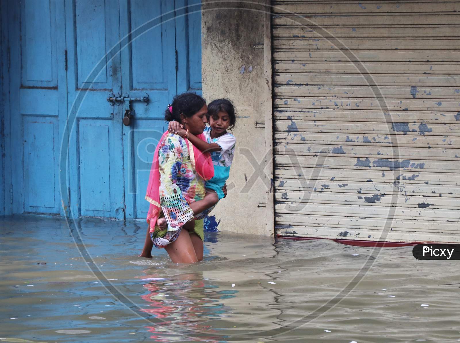 A woman carries a child through a waterlogged road after heavy rainfall in Mumbai, India, September 23, 2020.