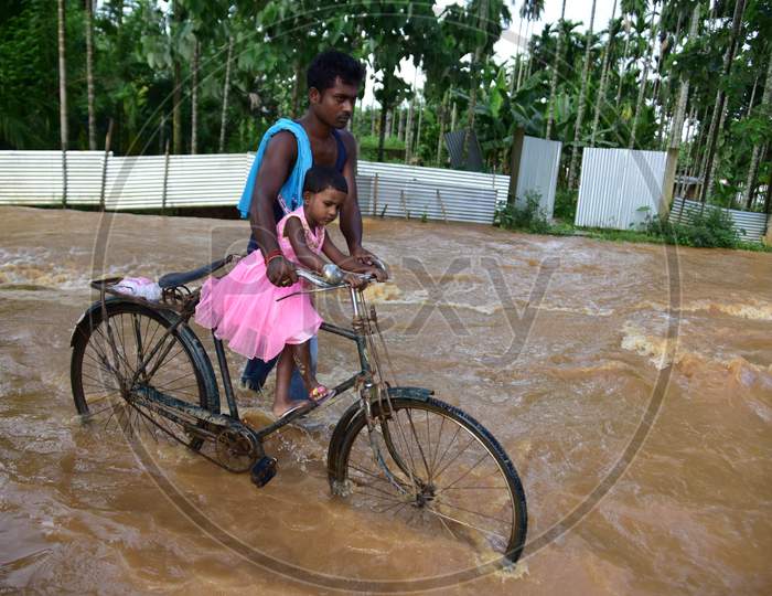 A man carries his daughter on a bicycle as he wades through a flooded area, following heavy rainfall, in Nagaon district, Sept. 25, 2020. (