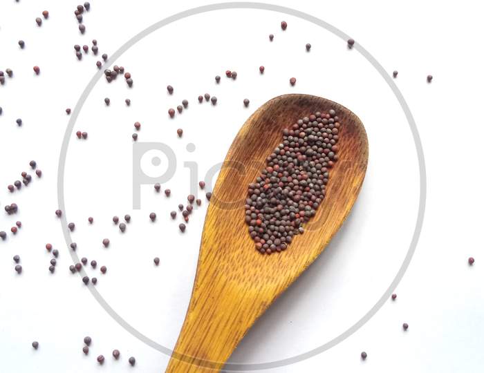Mustard seeds in wooden spoon isolated