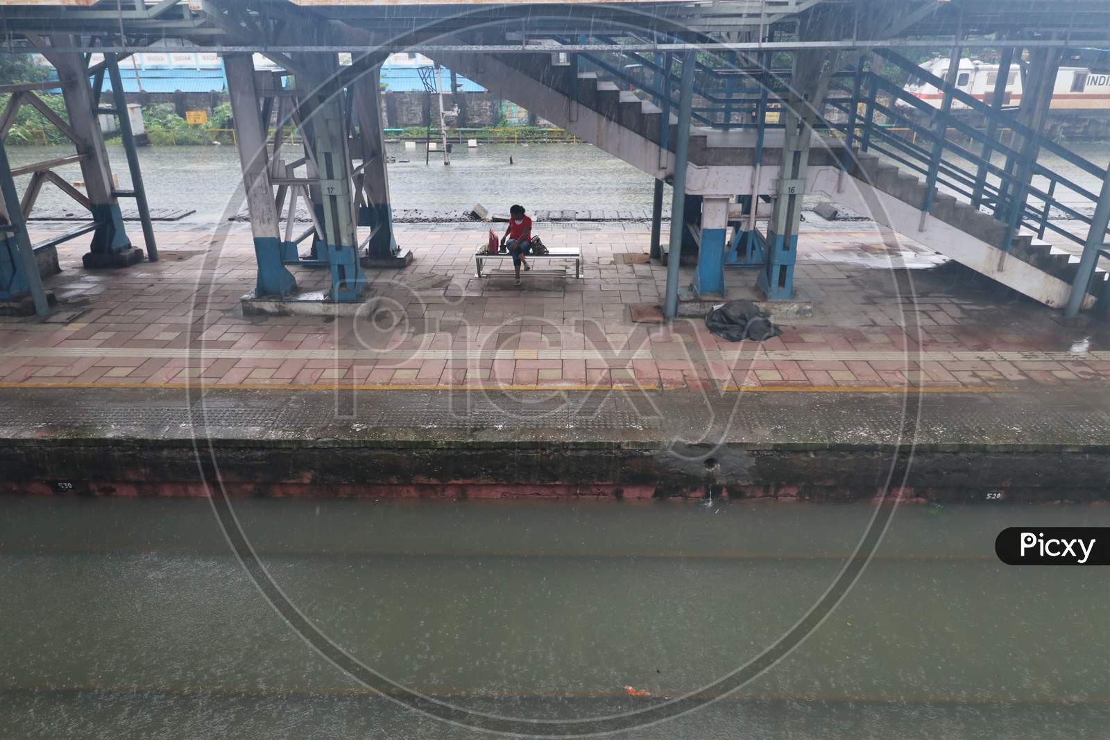 A woman sits on an empty platform as the tracks are seen waterlogged after heavy rainfall in Mumbai, India, September 23, 2020.
