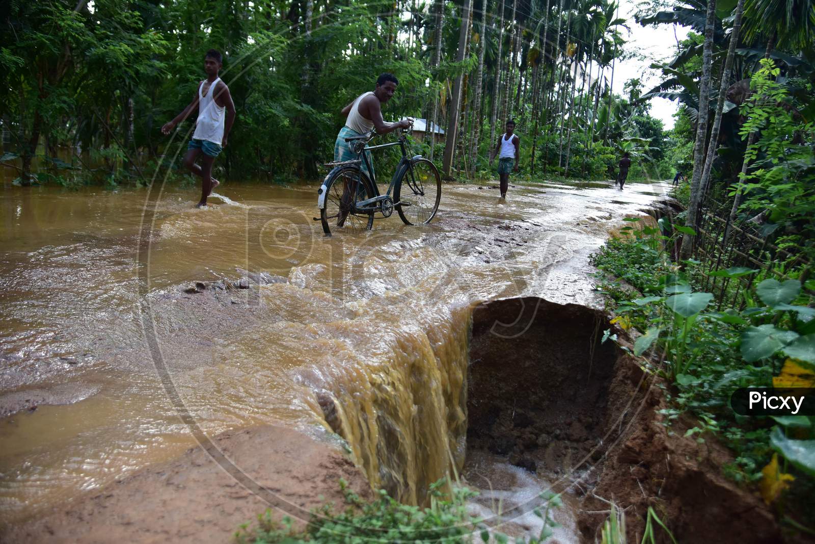 Villagers wade past a flood damaged road at  Juripar village near Kampur  in Nagaon District of Assam  on sep 25,2020.