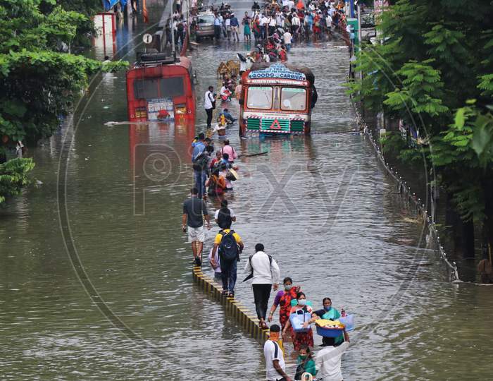 People wade through a waterlogged road after heavy rainfall in Mumbai, India, September 23, 2020.