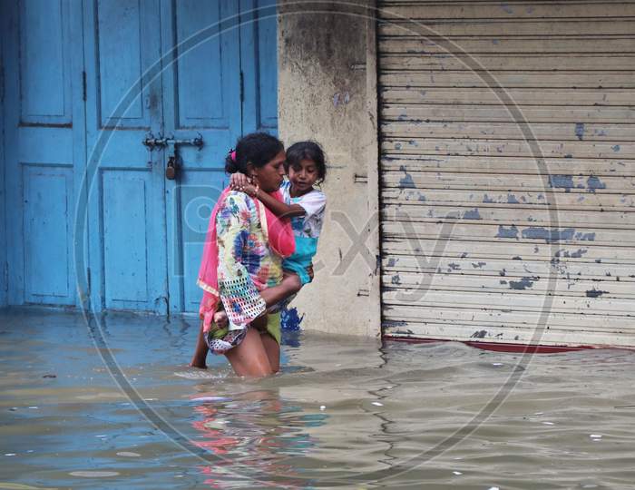 A woman carries a child through a waterlogged road after heavy rainfall in Mumbai, India, September 23, 2020.