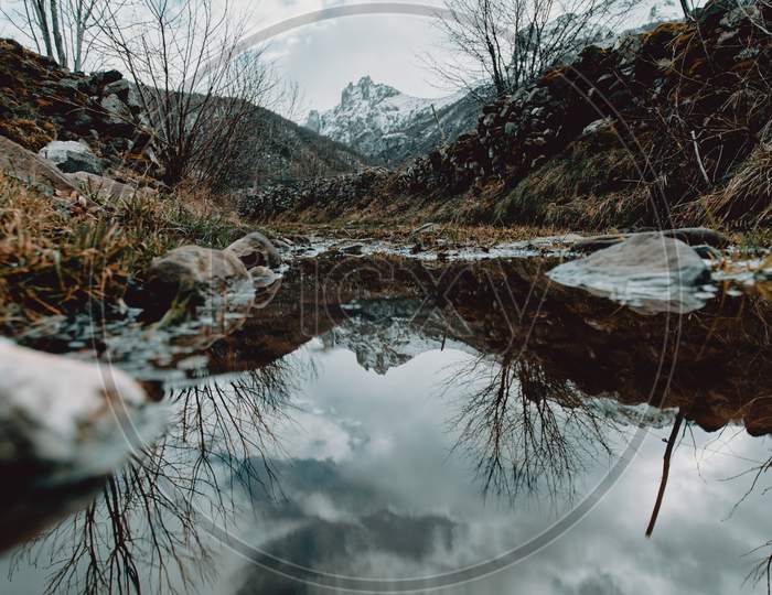 Mountains Reflecting In The Water In The Middle Of The Mountains During A Cloudy Day