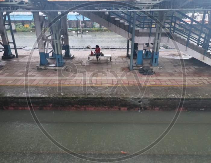 A woman sits on an empty platform as the tracks are seen waterlogged after heavy rainfall in Mumbai, India, September 23, 2020.