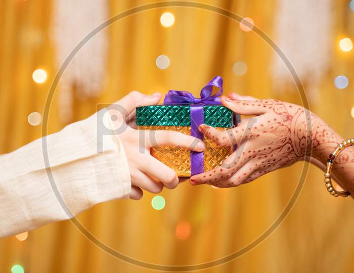 Close Up Of Brother Hands Giving Gift To Sister During During Raksha Bandhan, Bhai Dooj Or Bhaubeej Indian Religious Festival