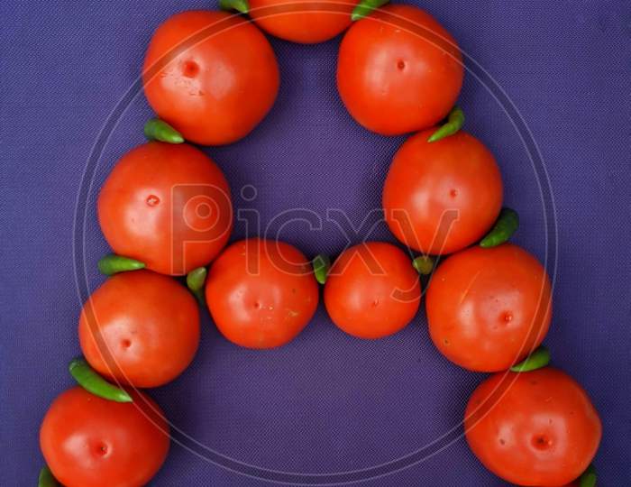 Capital letter A using green chillies and tomatoes.
