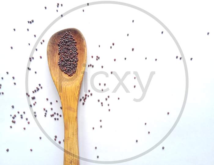 Mustard seeds in wooden spoon isolated in white background