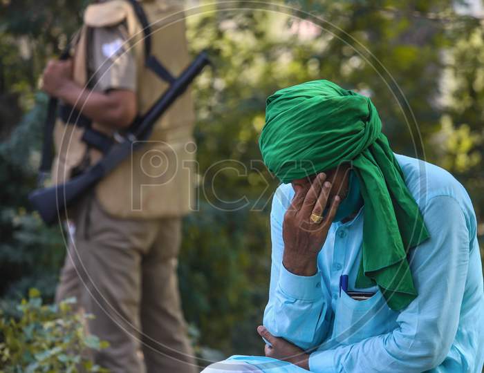 A farmer rests as police officers stand guard during a protest against farm bills passed by India's parliament, at the Delhi-Noida border, in New Delhi, India, September 25, 2020