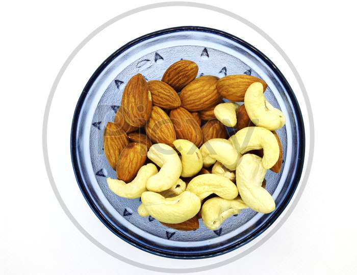 Fresh Mixed Almonds And Cashew Nuts In A Blue Bowl, Top View. White Isolated Background.