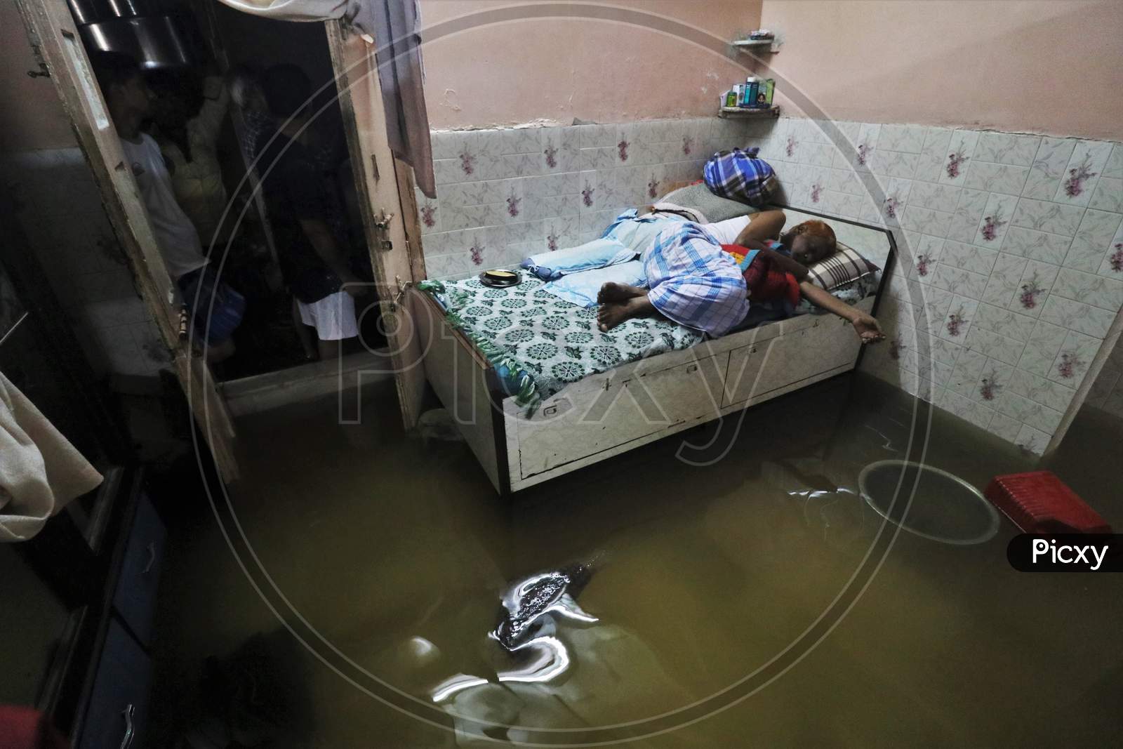 A man is seen sleeping on a bed inside his house that is waterlogged due heavy rains, in Mumbai, India on September 23, 2020.