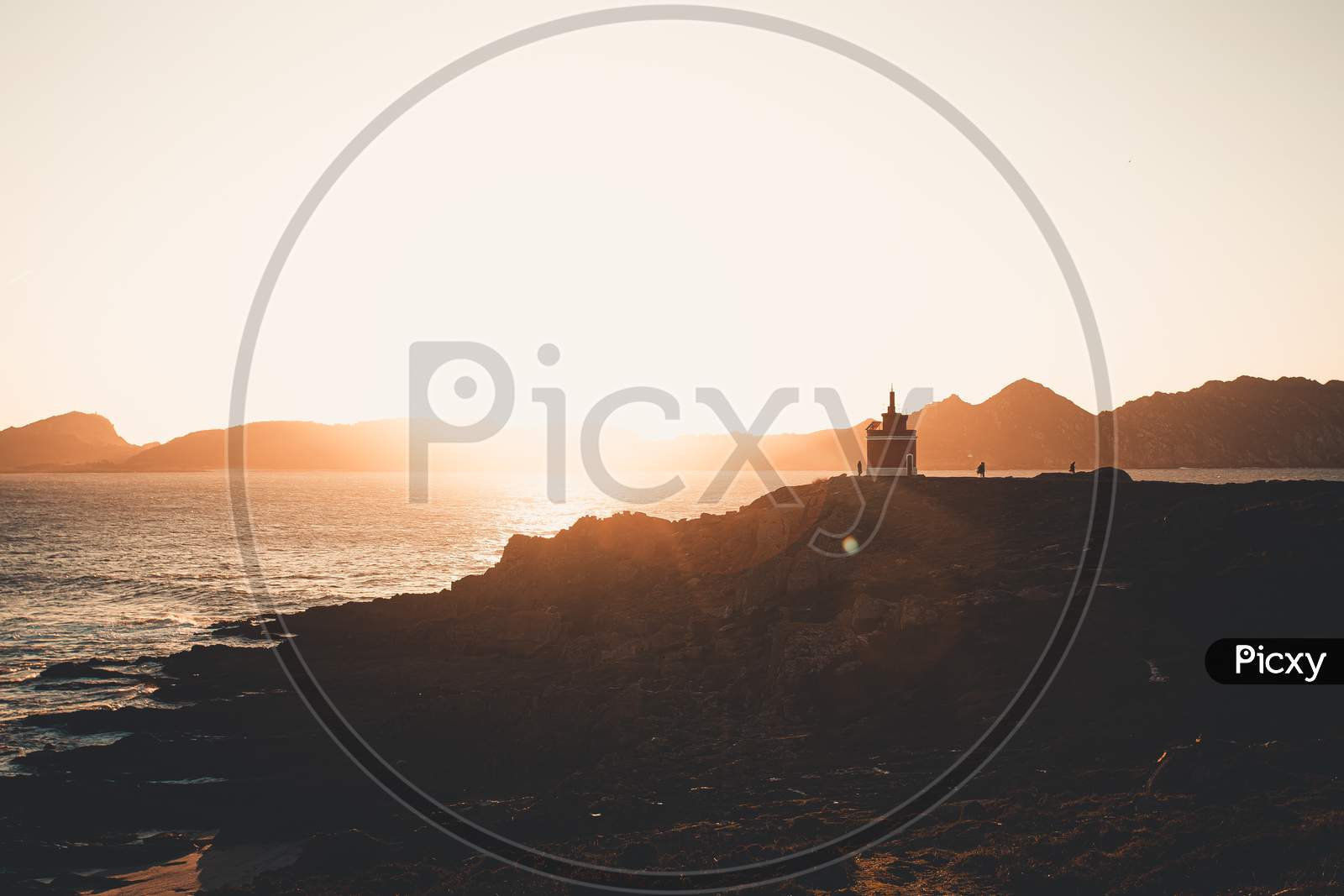 Red Lighthouse Under A Massive Sunset In The Coastline Of Spain During A Super Bright Day With Copy Space
