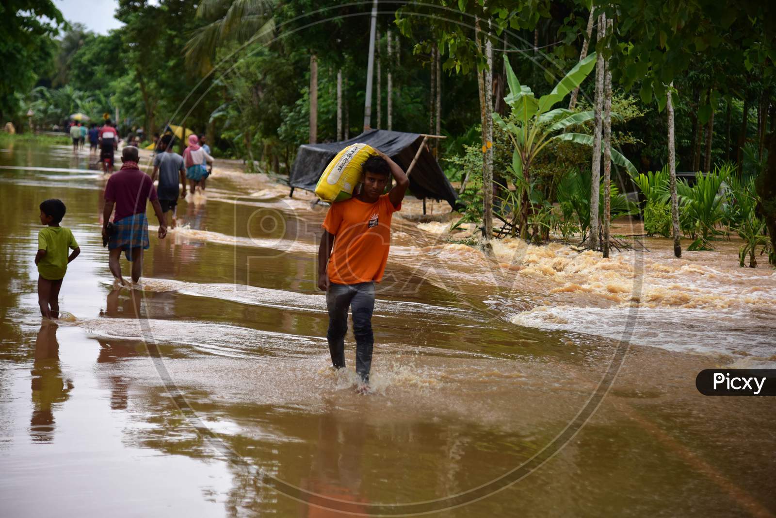 Villagers wade through water-logged road  to a safer place during heavy rain  at Kachua village  in Nagaon district, in the northeastern state of Assam on Sept 26,2020.