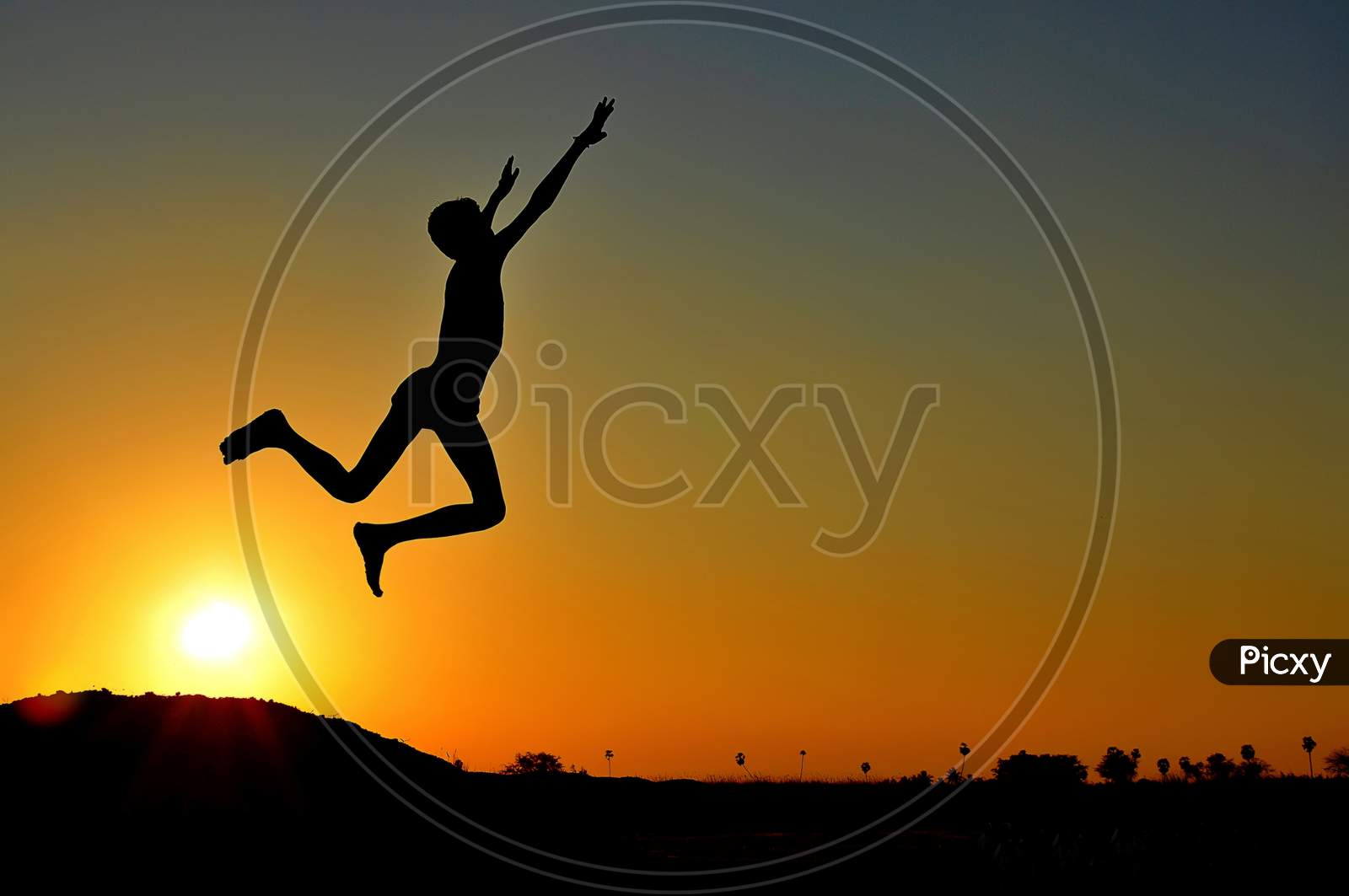 Silhouette of a jumping boy while the sunsets