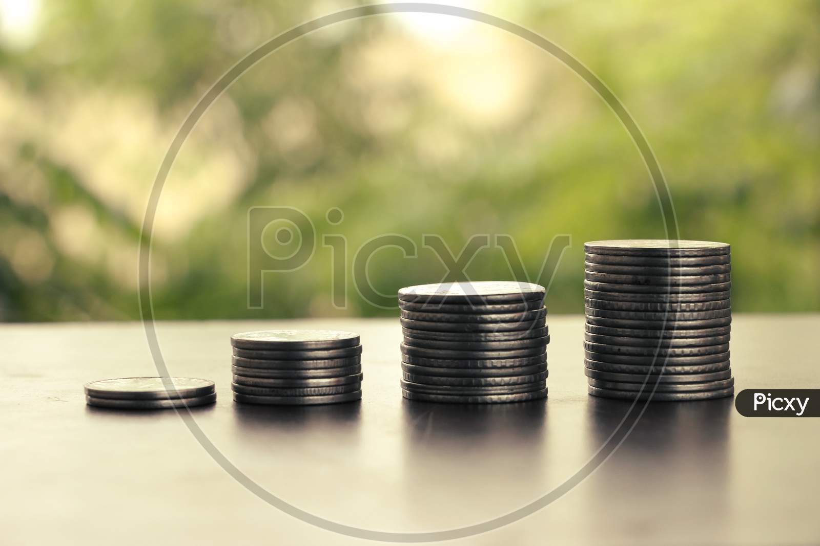 Money Coin Stack Growing Graph With Sun Light,Blurry Background, Plant On Coins, Silver Coin And Gold Coin, Investment Concept.Business Finance And Save Money Concept