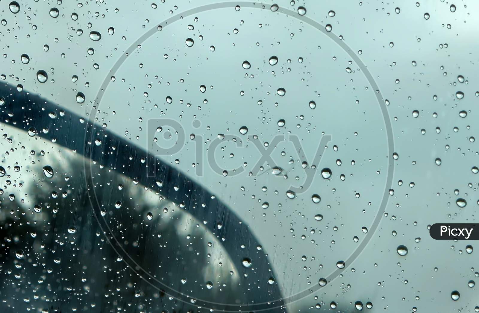 Rain Drops Running Down A Car Window In A Close Up View.