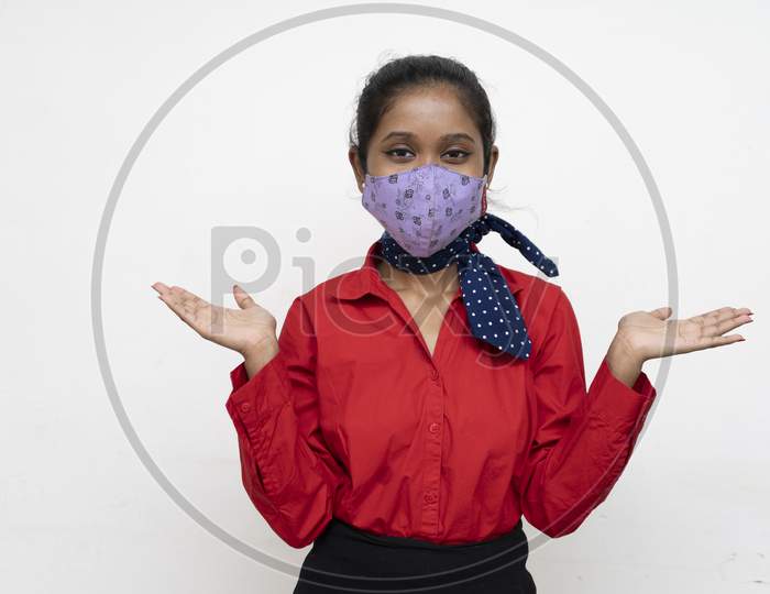 Young Charming Girl In Red Dress Wearing A Face Mask Standing In Front Of A White Wall With Copy Space.