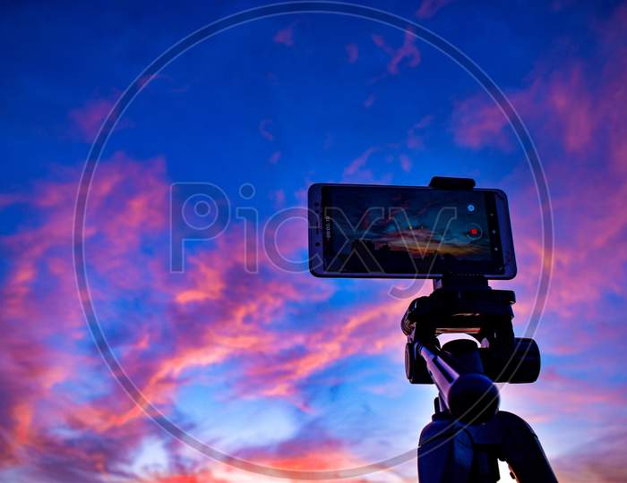 A Mobile Is Placed On A Tripod Stand With A Beautiful View On The Sky Behind. Reddish Blue Evening Sky