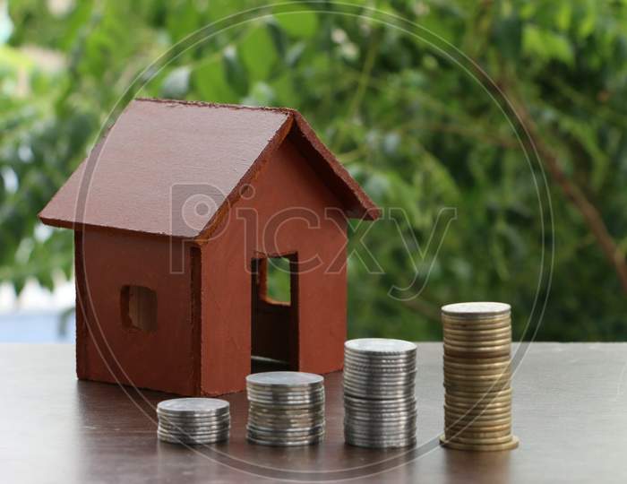 Money Coin Stack Growing Graph With Home Model On Wood Table In The Public Park Background.Saving Money And Investment Concept.