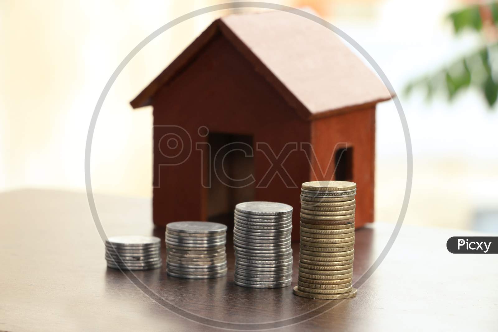 Money Coin Stack Growing Graph With Home Model On Wood Table In The Public Park Background. Saving Money And Investment Concept.
