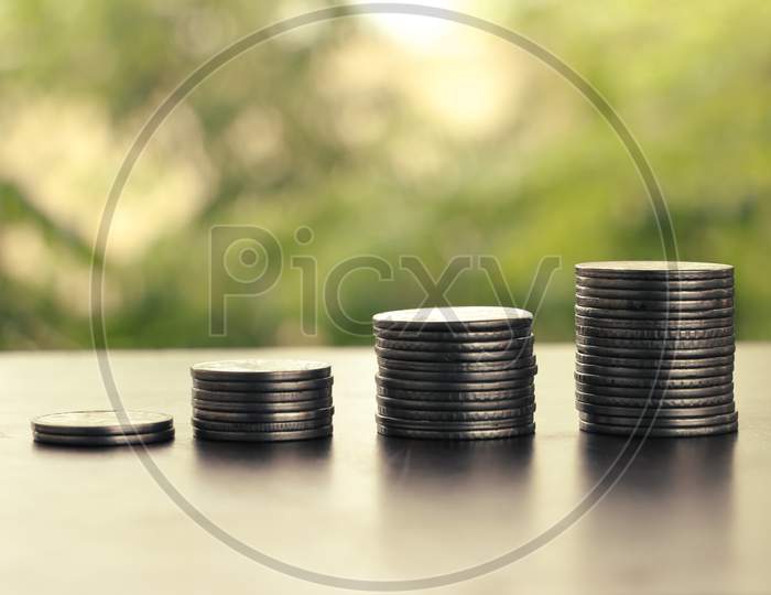 Money Coin Stack Growing Graph With Sun Light,Blurry Background, Plant On Coins, Silver Coin And Gold Coin, Investment Concept.Business Finance And Save Money Concept