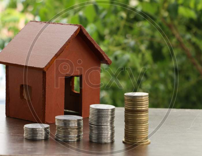 Money Coin Stack Growing Graph With Home Model On Wood Table In The Public Park Background.Saving Money And Investment Concept.