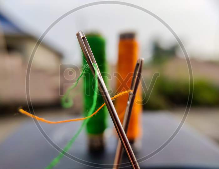 Green and orange fiber on sewing needles