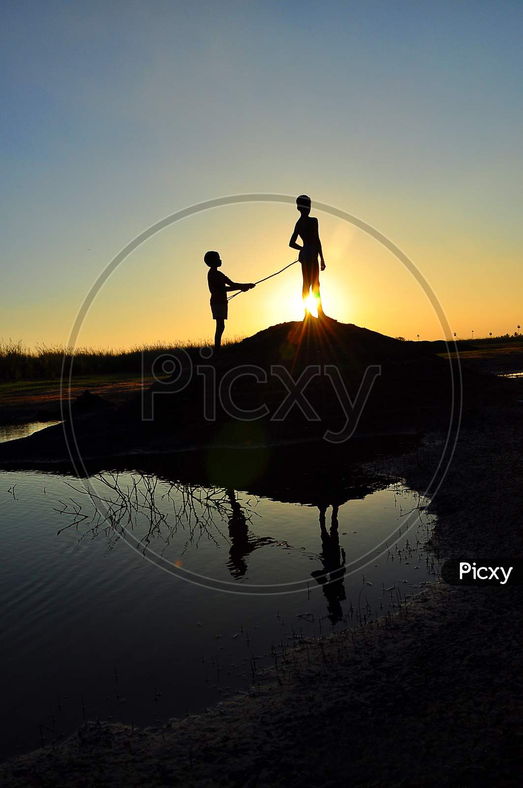 Silhouette of a  two boys near the lake while the sunsets