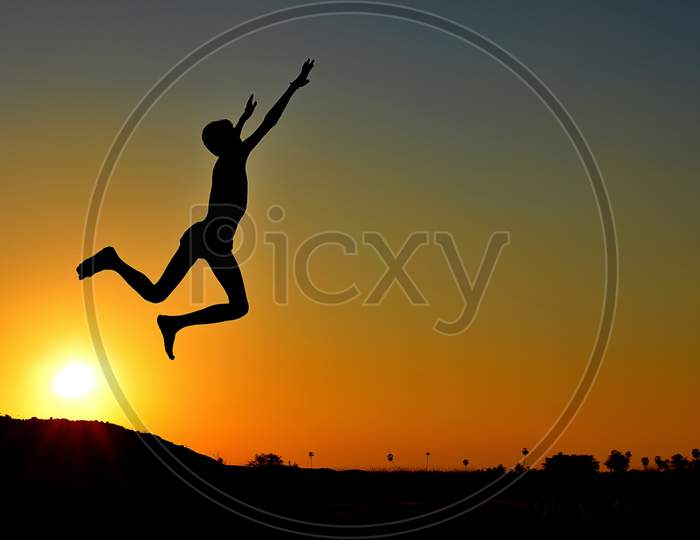 Silhouette of a jumping boy while the sunsets