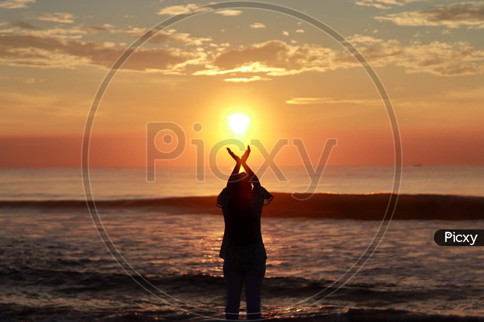 A Young Woman Silhouette Raising Her Hands Towards The Sky And Standing On The Sea Shore At Sunrise In The Morning, Welcoming And Thanking The Sun'S First Bright Ray